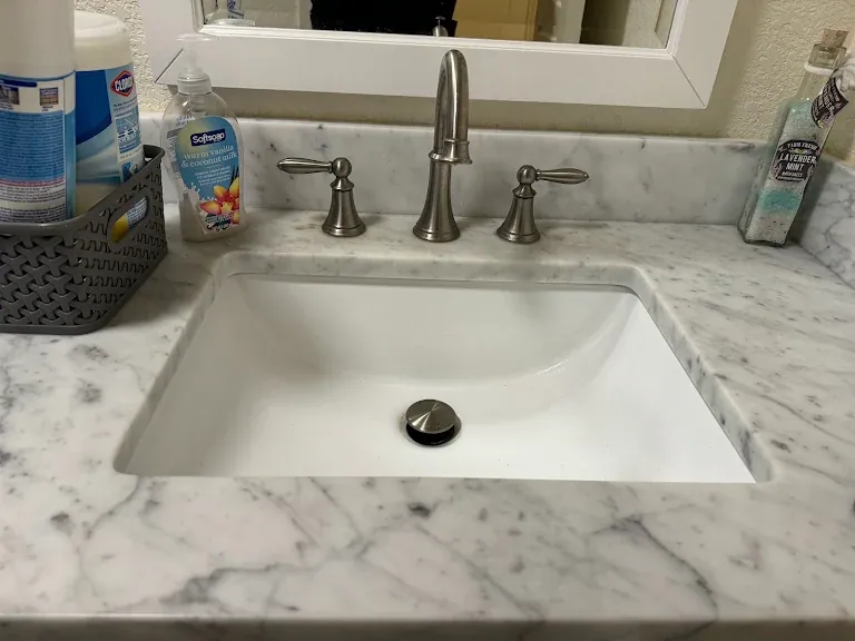 Widespread brushed nickel bathroom faucet on a marble vanity top