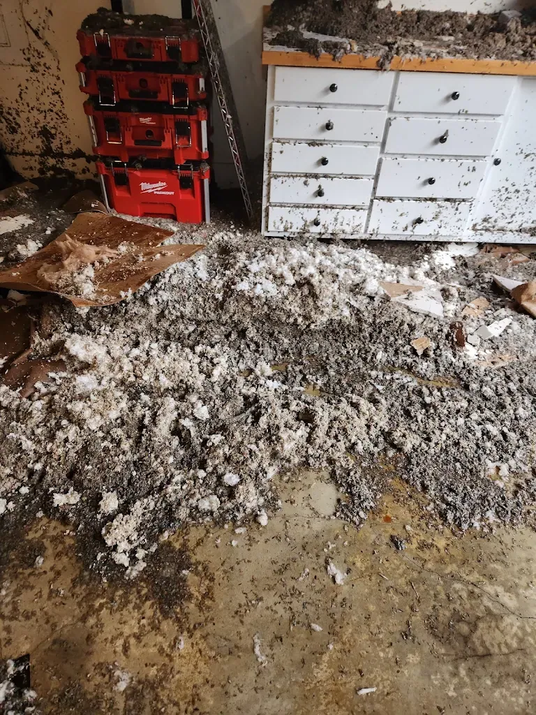 Garage floor covered in wet insulation and drywall debris after a pipe burst