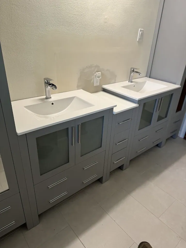 Gray double vanity with white sinks and chrome faucets installed in a bathroom