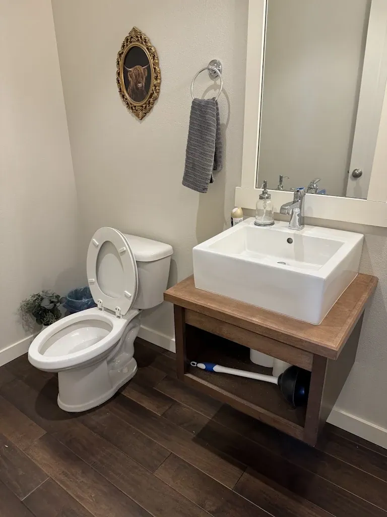 Powder room with vessel sink on a floating wood vanity and new toilet