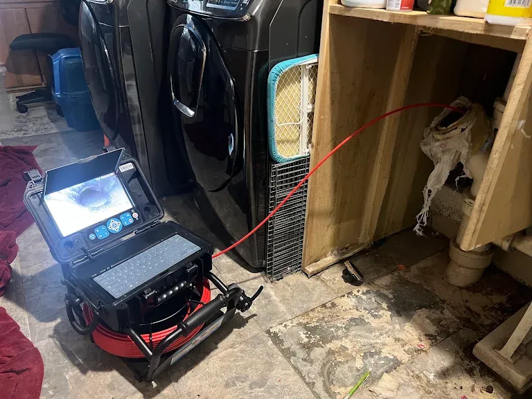 Sewer camera monitor showing inside of a drain pipe while the push camera is fed into a laundry room drain