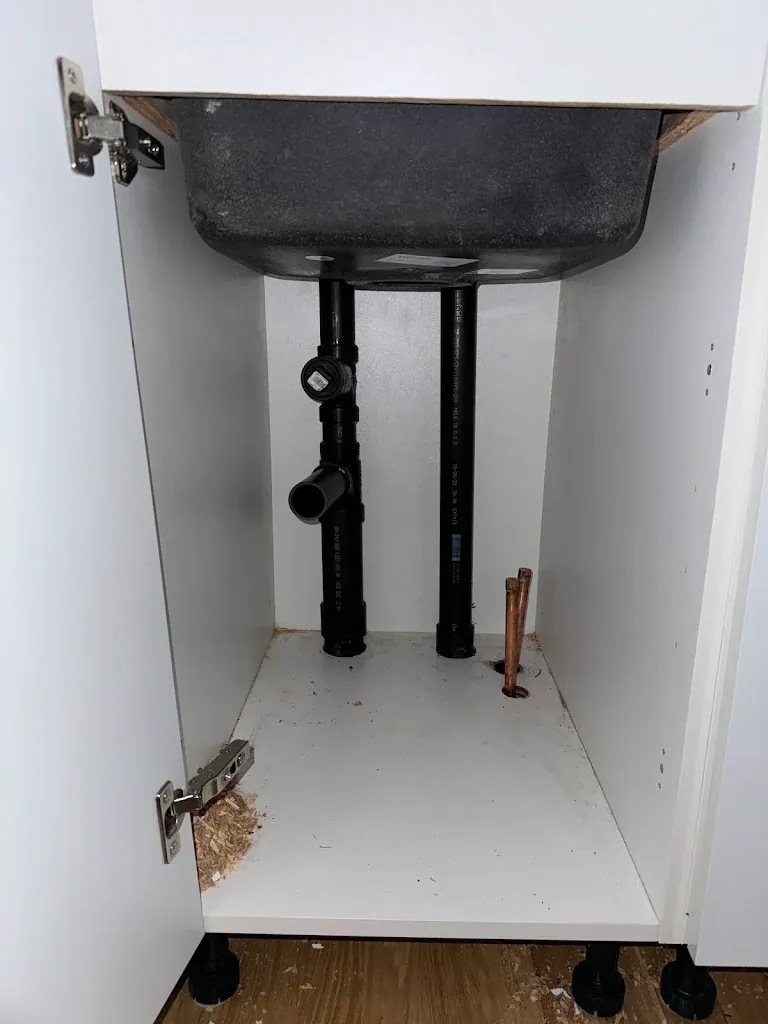 Under-cabinet view of new ABS drain and vent with copper supply stub