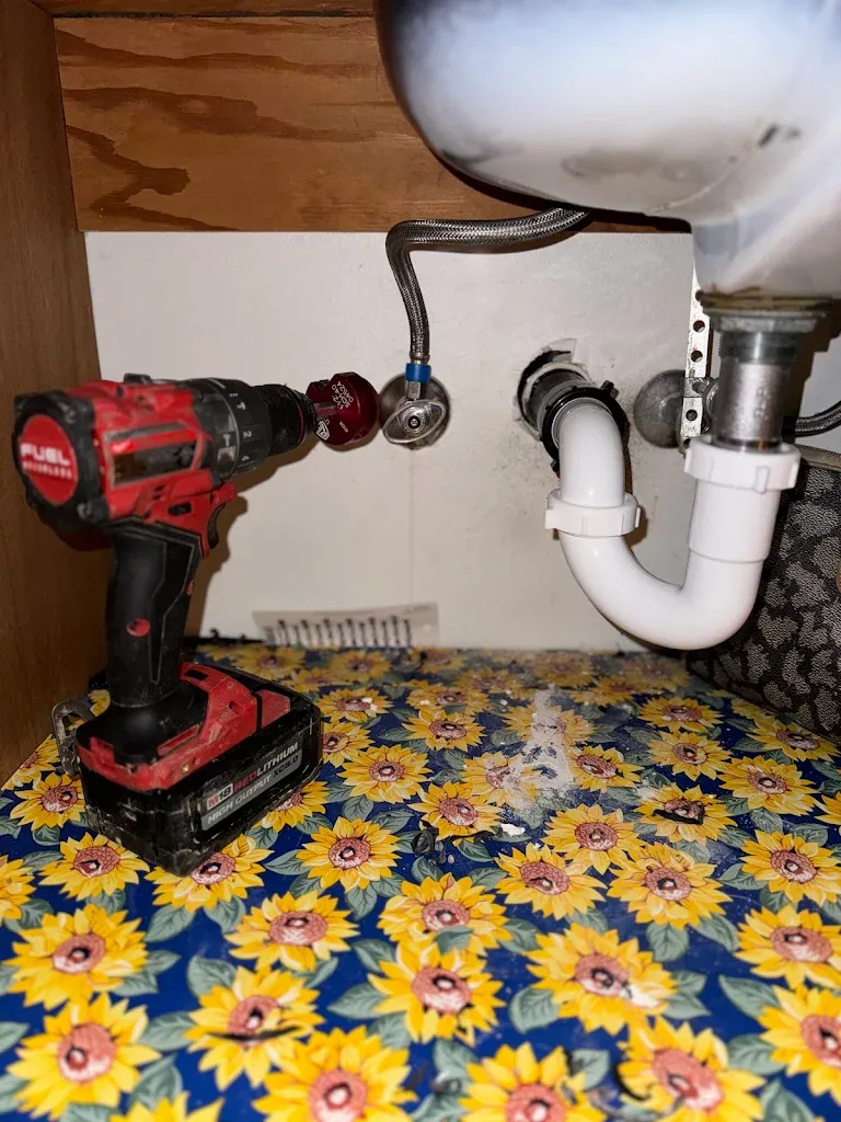 Under-sink angle stop, braided supply line and P-trap with a drill on the cabinet floor