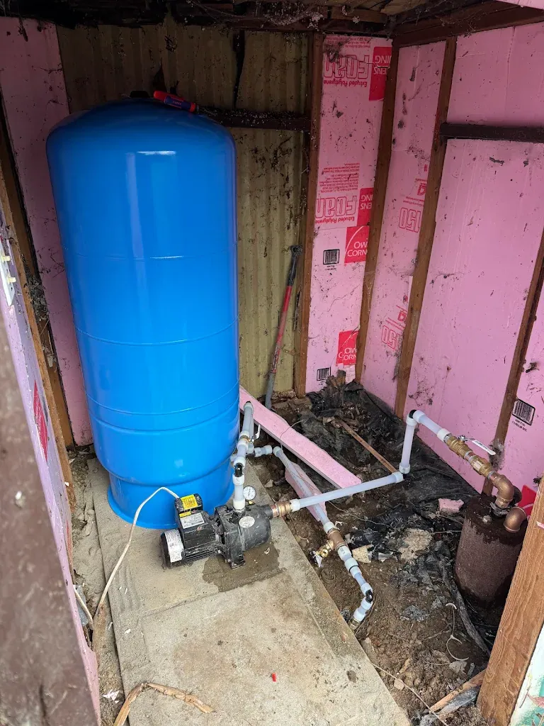 Blue well pressure tank with new tank tee, pressure switch and gauge plumbed in an insulated pump house