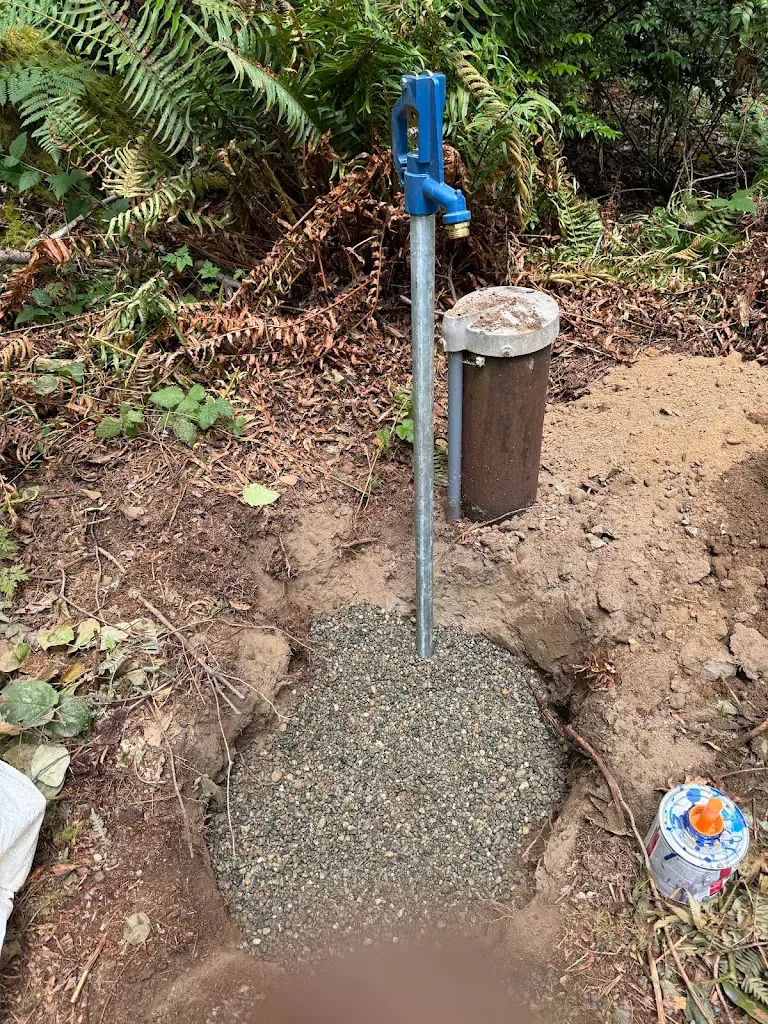 Frost-free yard hydrant set in a gravel drain bed next to a well casing